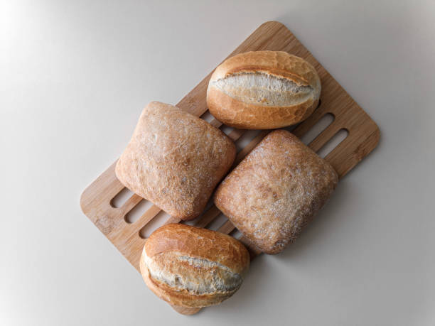 quattro panini giacciono su un supporto di legno su un tavolo bianco. - weat foto e immagini stock
