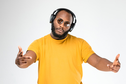 African-american ethnicity person at the studio with professional wireless black headphones is listening music. Concept for dj, pop, rap, r&b music photography. Portrait with sunglasses