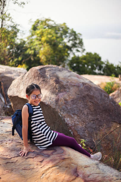 smiley portrait of a girl resting on a big rock during weekend hiking - pre teen boy flash imagens e fotografias de stock