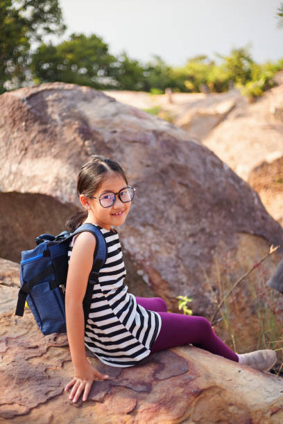 smiley portrait of a girl resting on the big rock during weekend hikin - pre teen boy flash imagens e fotografias de stock