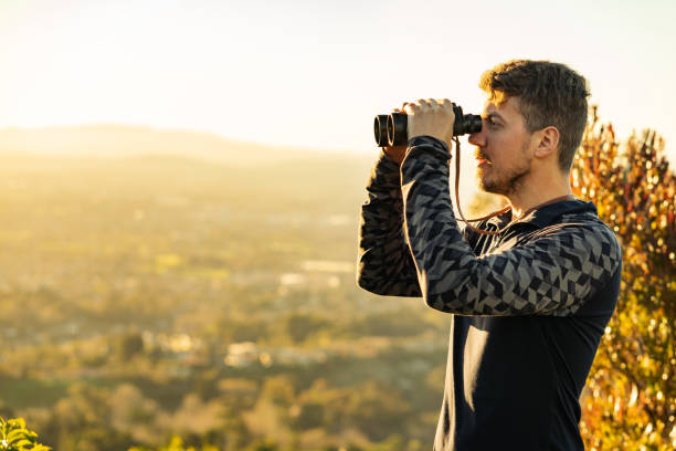 istock Young man using binoculars in the middle of the mountains 1324605295