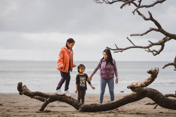 istock Mother with daughters hiking on beach , walking on log. 1324606454