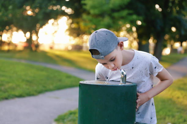 Thirsty kid outside Boy drinks tap water from public drinking fountain. Copy space for your text whites only drinking fountain stock pictures, royalty-free photos & images