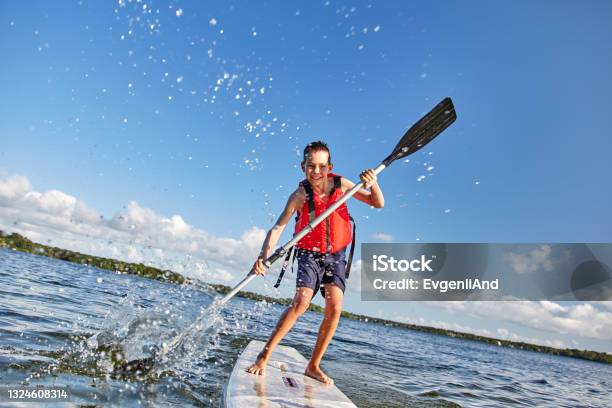Happy Boy Paddling On Stand Up Paddle Board Stock Photo - Download Image Now - Paddleboarding, Child, Paddleboard