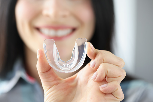 Mujer sonriente sostiene protector bucal de plástico transparente en la mano photo
