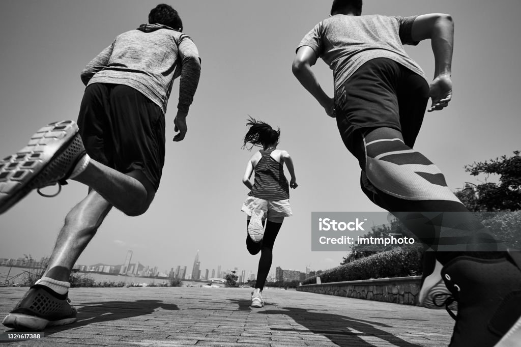 rear view of three asian runners running in seaside park three young asian adults running jogging outdoors, rear and low angle view, black and white Running Stock Photo