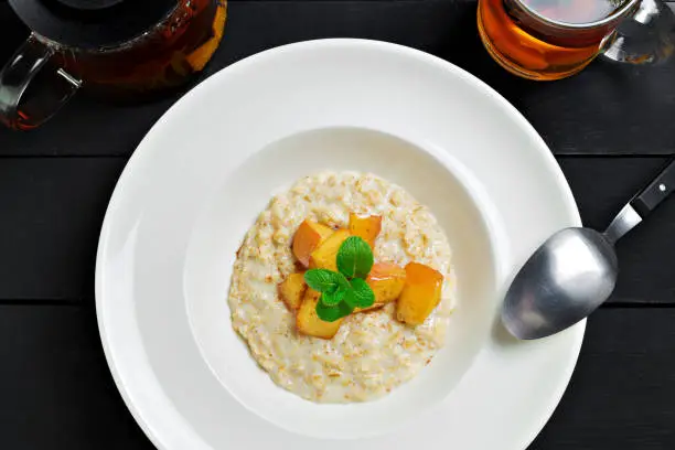 Oatmeal porridge with baked apple in white bowl, top view