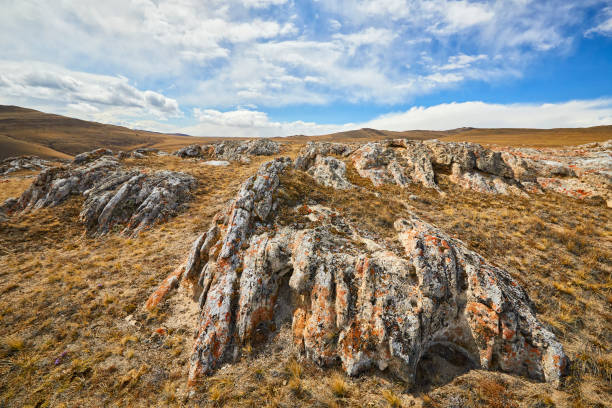 Steppe covered with rocks and blue sky with clouds
