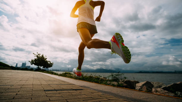 fitness-frau läuft training für marathon auf sonnigen küstenweg - aktiver lebensstil stock-fotos und bilder