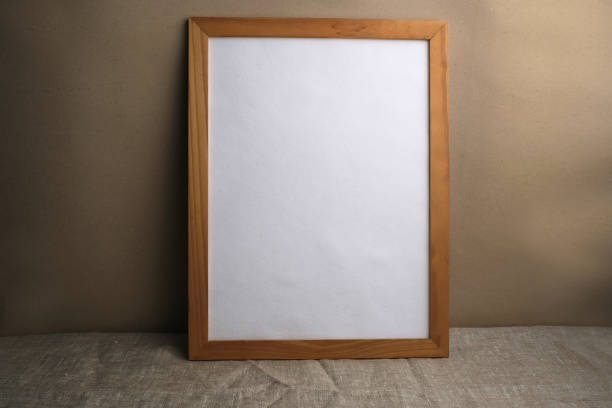 istock White paper in a wooden frame on a table covered with linen canvas. Mockup. 1324625501