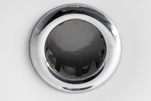 Close-up of a drain hole in a white ceramic sink.