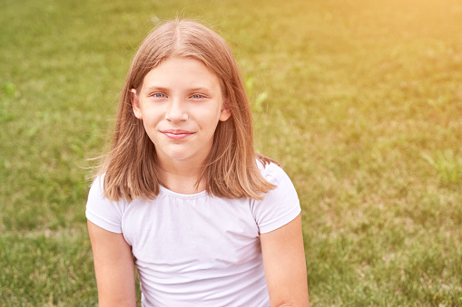Little girl portrait. Outdoor green background. Looking. Teenager schoolgirl at park. Cute face. Children beauty. Female head. Charisma caucasian