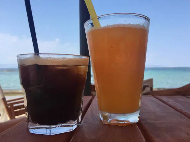 Photo of A greek favorite on the Avra Beach: Freddo Espresso (Greece’s most popular summer coffee drink) and orange juice - Aegina Island, Greece.