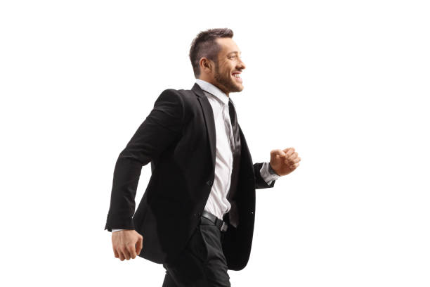 istock Young businessman in a black suit running and smiling 1324635888