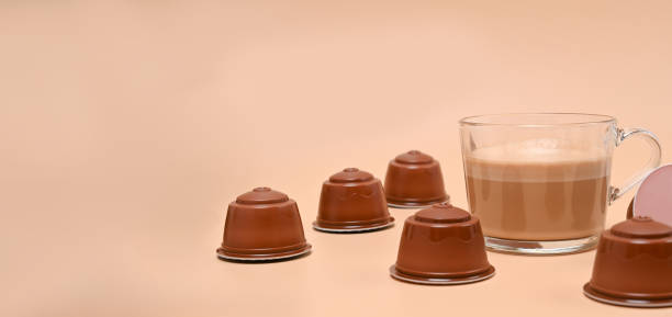 istock Cup of coffee and coffee capsules on beige background. 1324635937