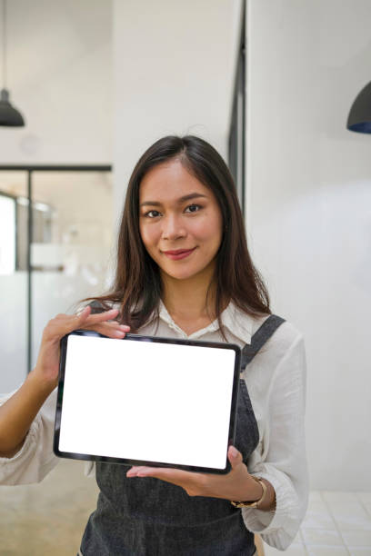 istock Cheerful young female owner showing digital tablet while standing in coffee shop. 1324636010