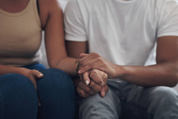 cropped shot of an unrecognizable couple sitting inside together and holding hands - holding hands human hand romance support imagens e fotografias de stock