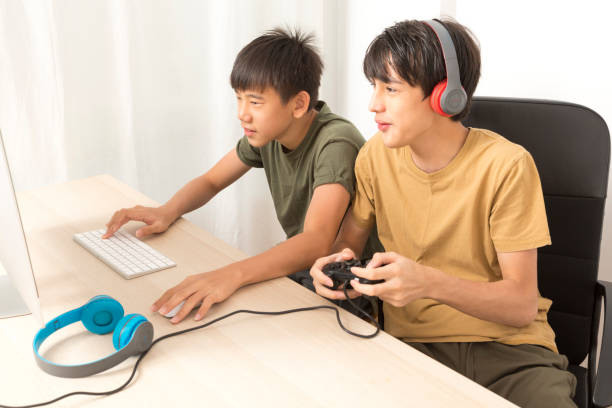 istock Two teenage boys with headphone using computers to play online gaming at home. 1324637497