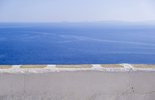 Calm sea, clear blue sky, view over a white stone parapet wall. Spectacular view to Aegean Sea, Cyclades Greece. Folegandros island outlook terrace. Copy space, summer vacations card template