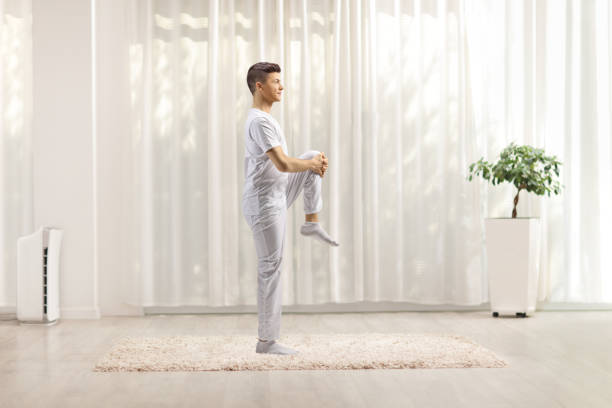 istock Young man in white clothes streching leg in a room 1324639774