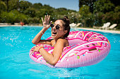 A beautiful girl in the pool on an inflatable donut is having fun on a hot summer day