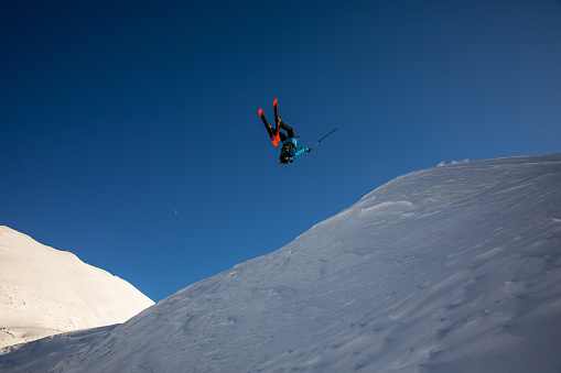 A Japanese snowboard rider does a jump on a sunny day with the sun behind him.