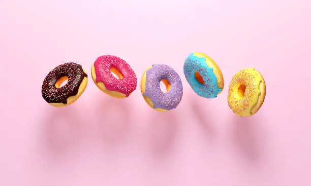 Photo of Colorful donuts flying on pink background.