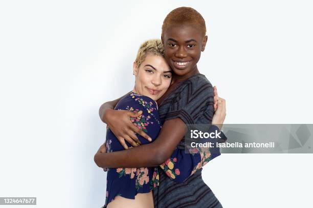 Photo Of Joyful Ladies Embrace And Enjoy Togetherness Being Of Different Of Races Dressed In Casual Jumpers Isolated Over White Background Stock Photo - Download Image Now