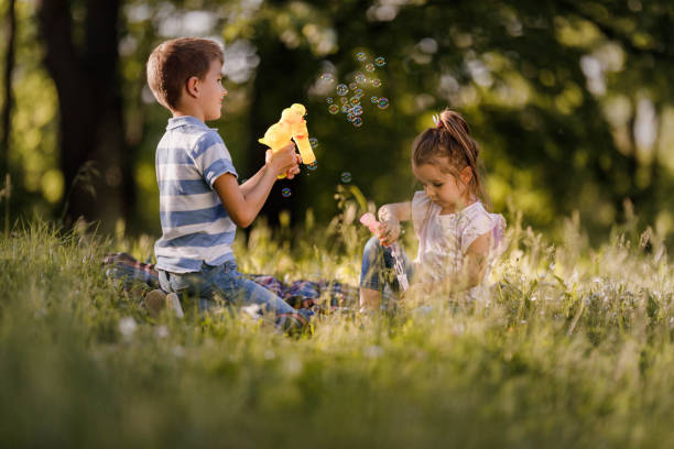 istock Two little kids making bubbles in spring day at the park. 1324652188