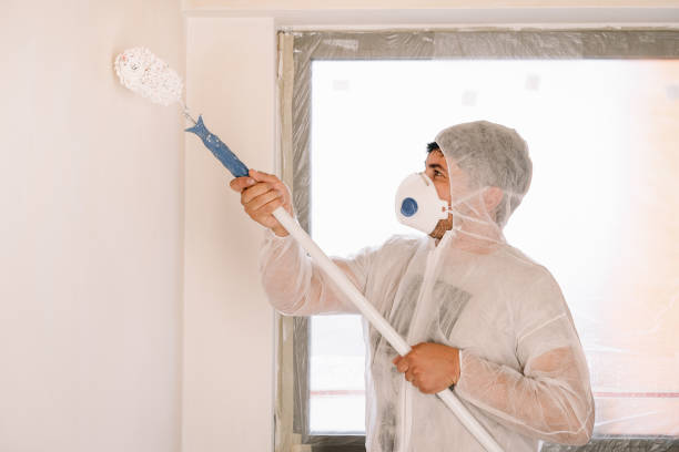 istock Man In Protective Workwear And Mask Working With Paint Roller Standing Against White Wall At Home 1324656195
