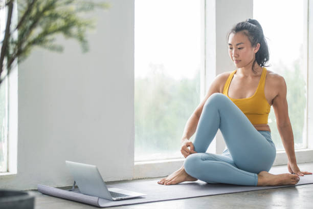 Female Asian Yoga instructor conducting an online class with laptop stock photo