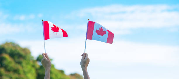 istock hand holding Canada flag on blue sky background. Canada Day  and happy celebration concepts 1324657461