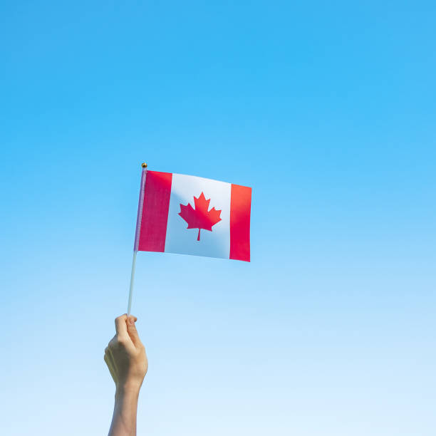 istock hand holding Canada flag on blue sky background. Canada Day  and happy celebration concepts 1324657525