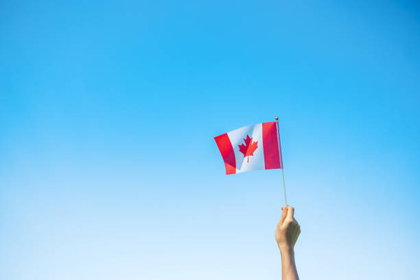 istock hand holding Canada flag on blue sky background. Canada Day  and happy celebration concepts 1324657614