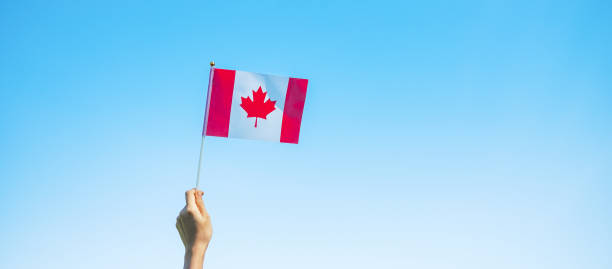 istock hand holding Canada flag on blue sky background. Canada Day  and happy celebration concepts 1324657682