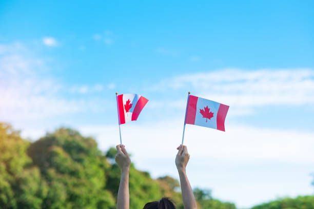 istock hand holding Canada flag on blue sky background. Canada Day  and happy celebration concepts 1324657803