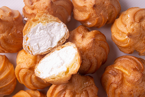 Slices of profiteroles with cream on a food background of profiteroles. Flat lay.