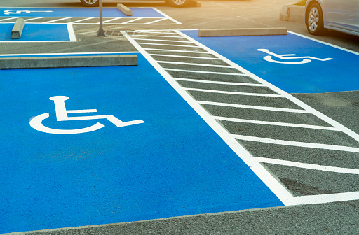 Asphalt car parking lot reserved for handicapped driver in supermarket or shopping mall. Car parking space for disabled people. Wheelchair sign paint on asphalt parking area. Handicapped parking lot.