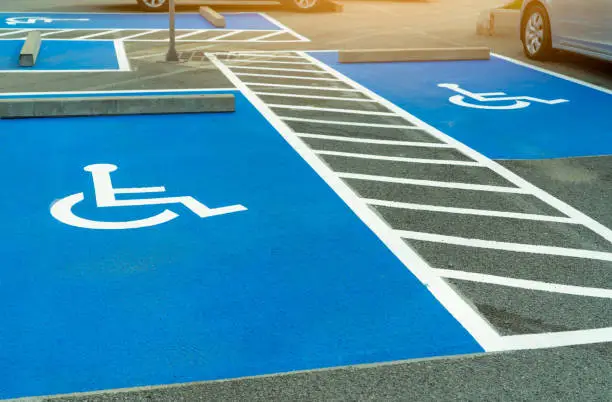 Photo of Asphalt car parking lot reserved for handicapped driver in supermarket or shopping mall. Car parking space for disabled people. Wheelchair sign paint on asphalt parking area. Handicapped parking lot.
