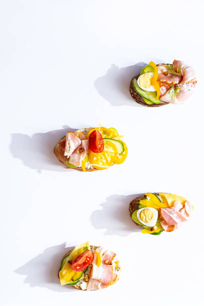 istock Various sandwiches for breakfast. Ready-to-eat appetizers with curd cheese, quail eggs, tomatoes, bacon, cucumber, bread sandwiches. Healthy snacks. Flat lay on a light background. 1324662135