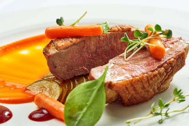 istock Appetizing confit duck breast with pear and yellow apple puree, berry sauce in a white plate. Isolated on grey background. 1324664607