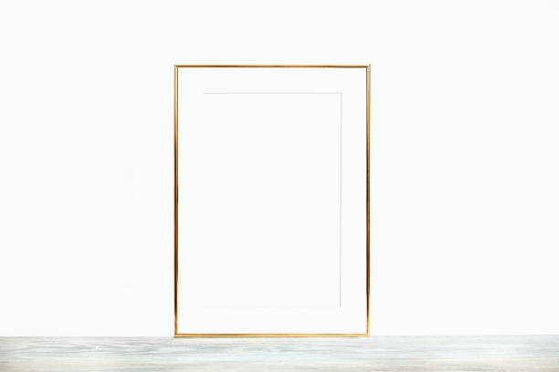 istock Thin gold frame with passepartout on a wooden table against a white wall 1324667700