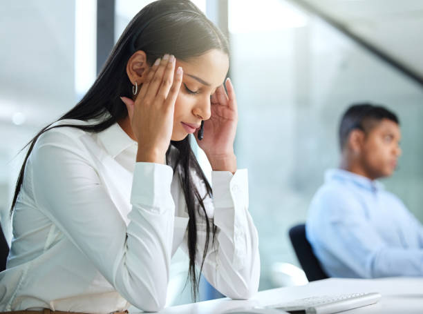 istock Shot of a young call centre agent sitting in the office and suffering from a headache while wearing a headset 1324669201