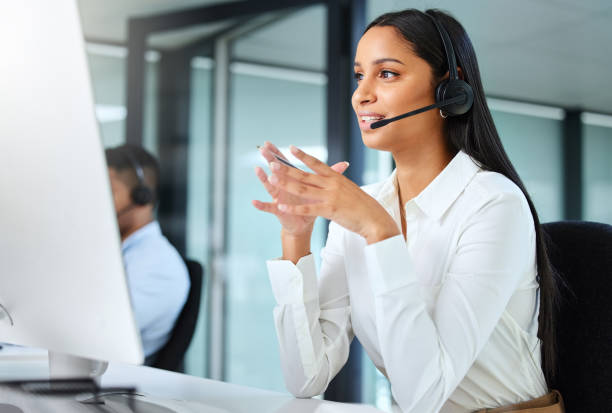 istock Shot of a young call centre agent sitting at her desk and explaining to a client while wearing a headset 1324669234