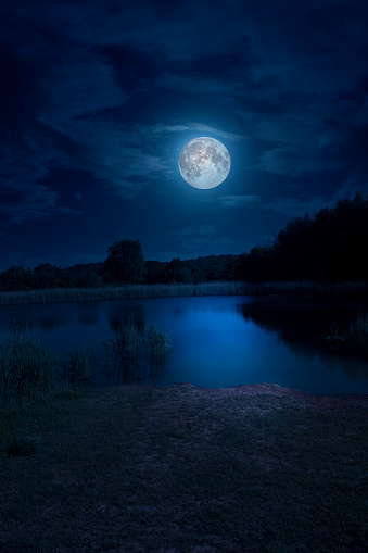 Composite image of a full moon over a small lake in natural parkland near Teversal, Nottinghamshire, England.