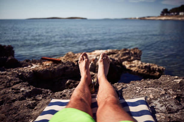 Man sunbathing on a rocky sea ocean beach.