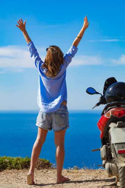 istock Woman with scooter looking at the distant sea horizon. 1324677682