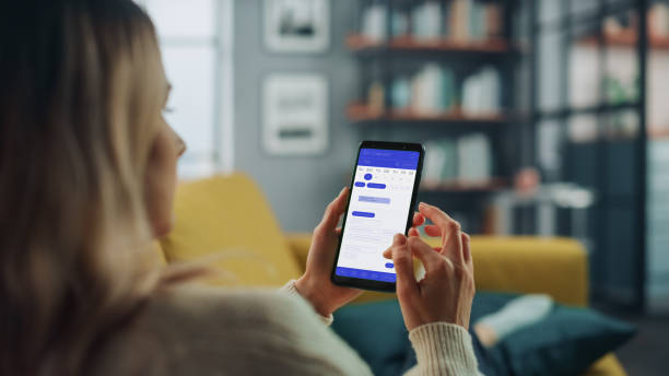 istock Beautiful Authentic Female Using a Smartphone with Calendar Application at Home Living Room while Lying on a Couch Sofa. She's Making Plans and Checking Event Schedule for a Day. 1324677969