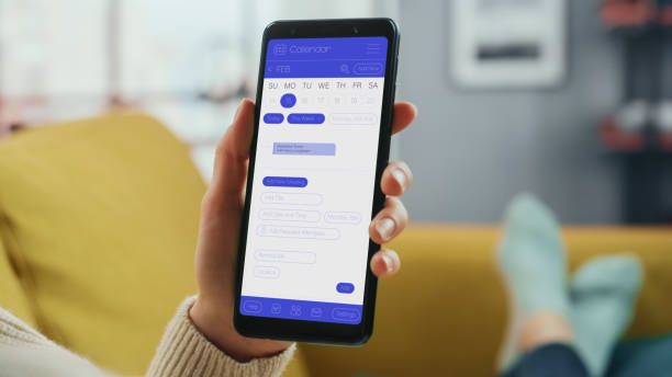 istock Beautiful Authentic Female Using a Smartphone with Calendar Application at Home Living Room while Lying on a Couch Sofa. She's Making Plans and Checking Event Schedule for a Day. 1324678143