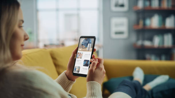 istock Beautiful Authentic Female Using a Smartphone for Reading Latest News and Articles about Technology. She is Lying on a Couch at Home Living Room. Freelancer Working From Home, Surfing the Internet. 1324678155